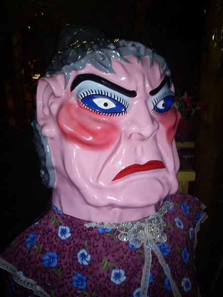Exaggerated festival doll with stern face and floral outfit.