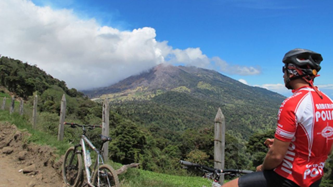 Cyclist resting on a mountain trail under a blue sky in Costa Rica.