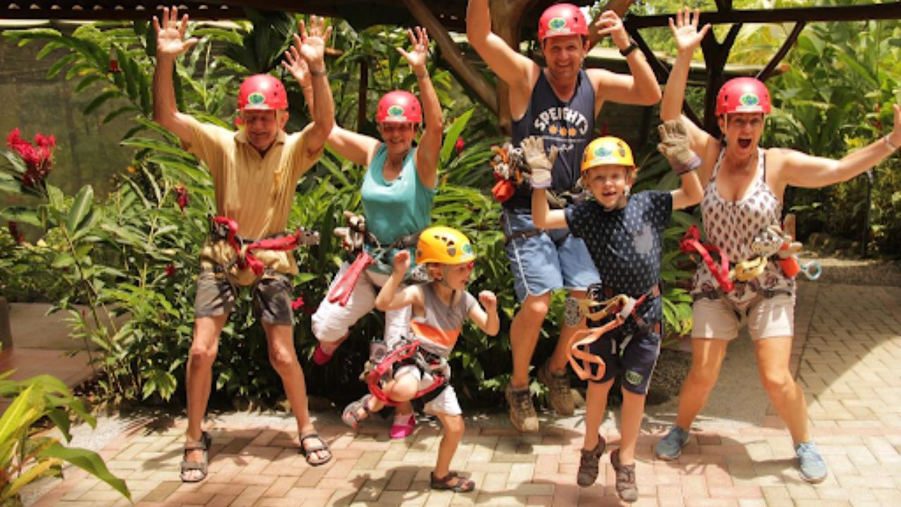 A family jumping and celebrating before a ziplining adventure in a tropical rainforest setting.